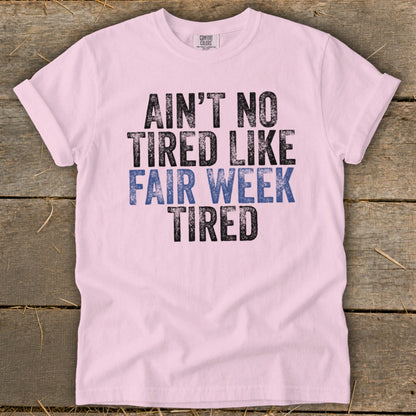 Pink t-shirt with text "AIN'T NO TIRED LIKE FAIR WEEK TIRED".