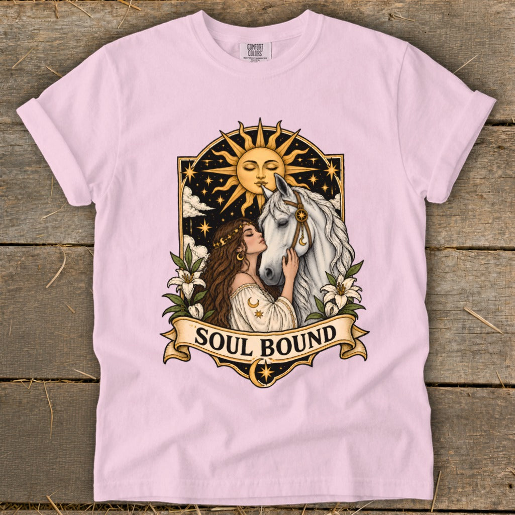Pink t-shirt featuring a woman embracing a white horse under a sun and starry sky with "Soul Bound" text.