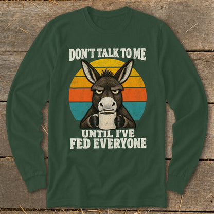 Dark green long-sleeved shirt with a graphic of a grumpy donkey holding a coffee mug against a retro sunset.