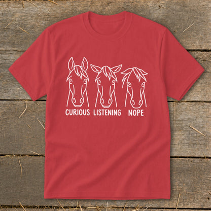 A red t-shirt printed with three horse heads and the text "CURIOUS," "LISTENING," and "NOPE."