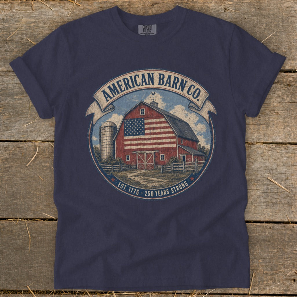 Navy t-shirt graphic with a red barn, silo, and flag. "American Barn Co." and "Established 1776, 250 Years Strong."