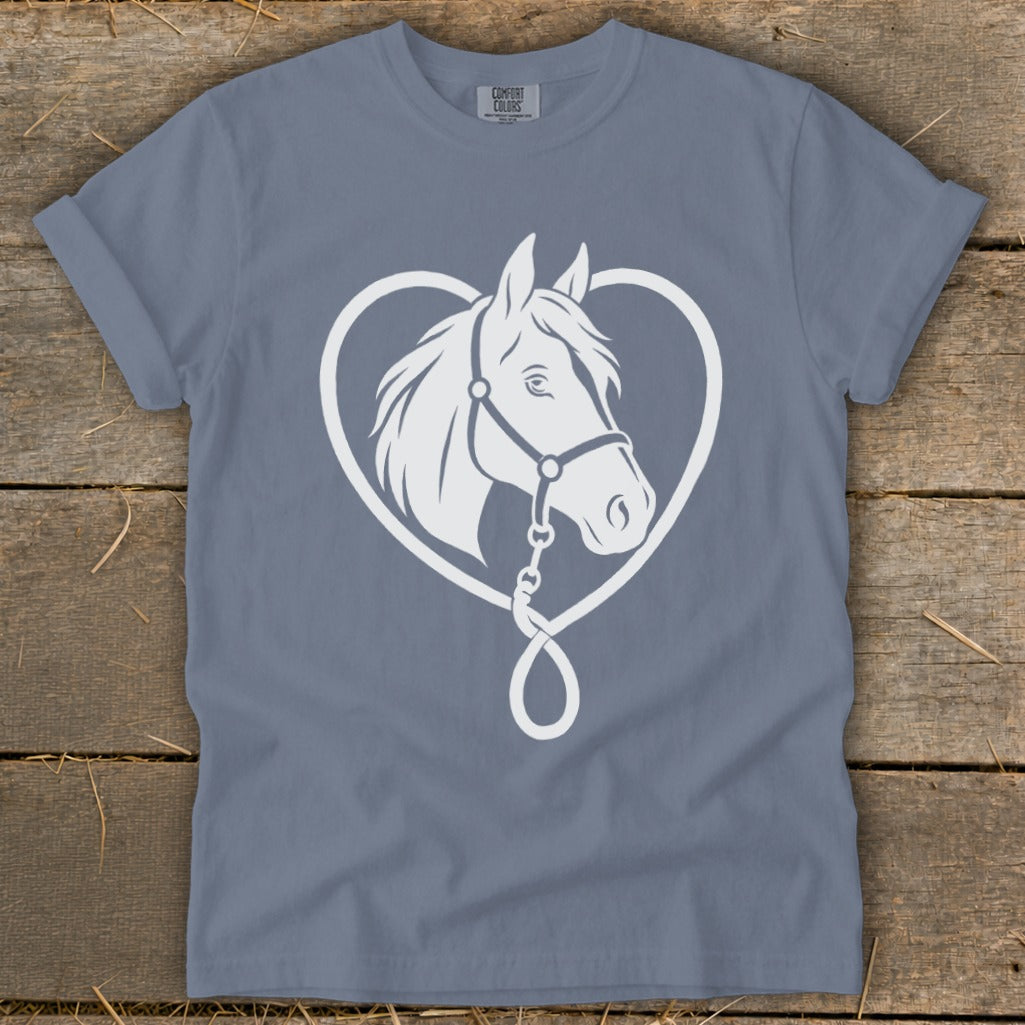 A slate blue t-shirt featuring a white graphic of a horse head inside a heart on a wooden background.