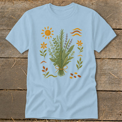 Light blue t-shirt with a botanical illustration featuring herbs, flowers, sun, and wavy lines.