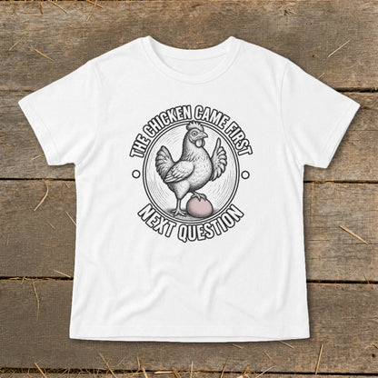 White t-shirt with a circular graphic of a chicken on an egg, text reads "The chicken came first. Next question."