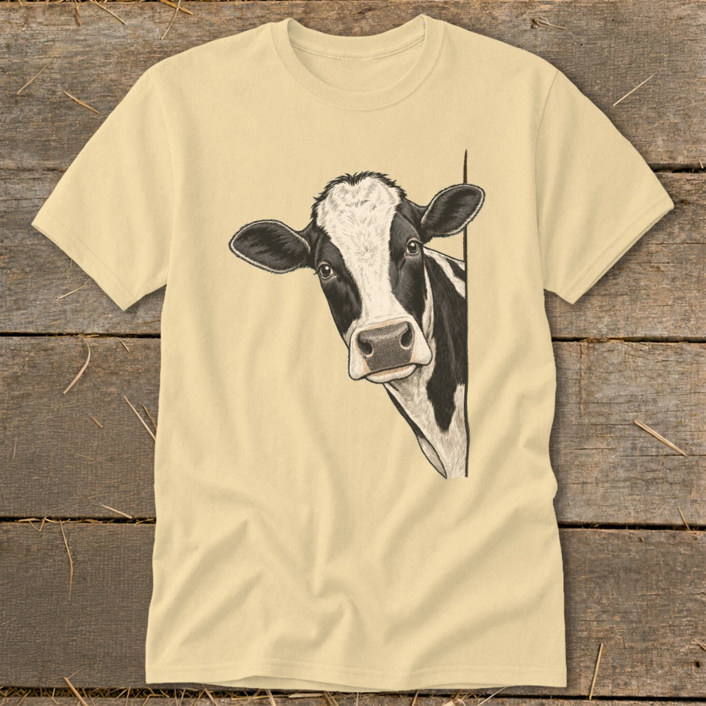 Black and white cow peeking around a corner on a light yellow t-shirt.
