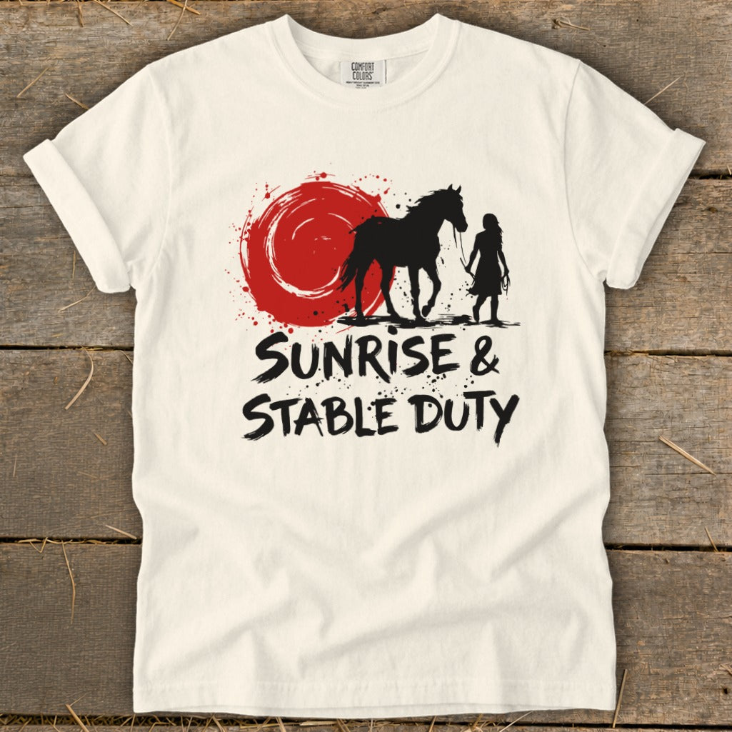 Cream t-shirt with black silhouette of horse and rider next to a red circle with splatter. Text reads "Sunrise & Stable Duty".