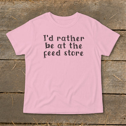 Pink t-shirt with black text that reads "I'd rather be at the feed store."