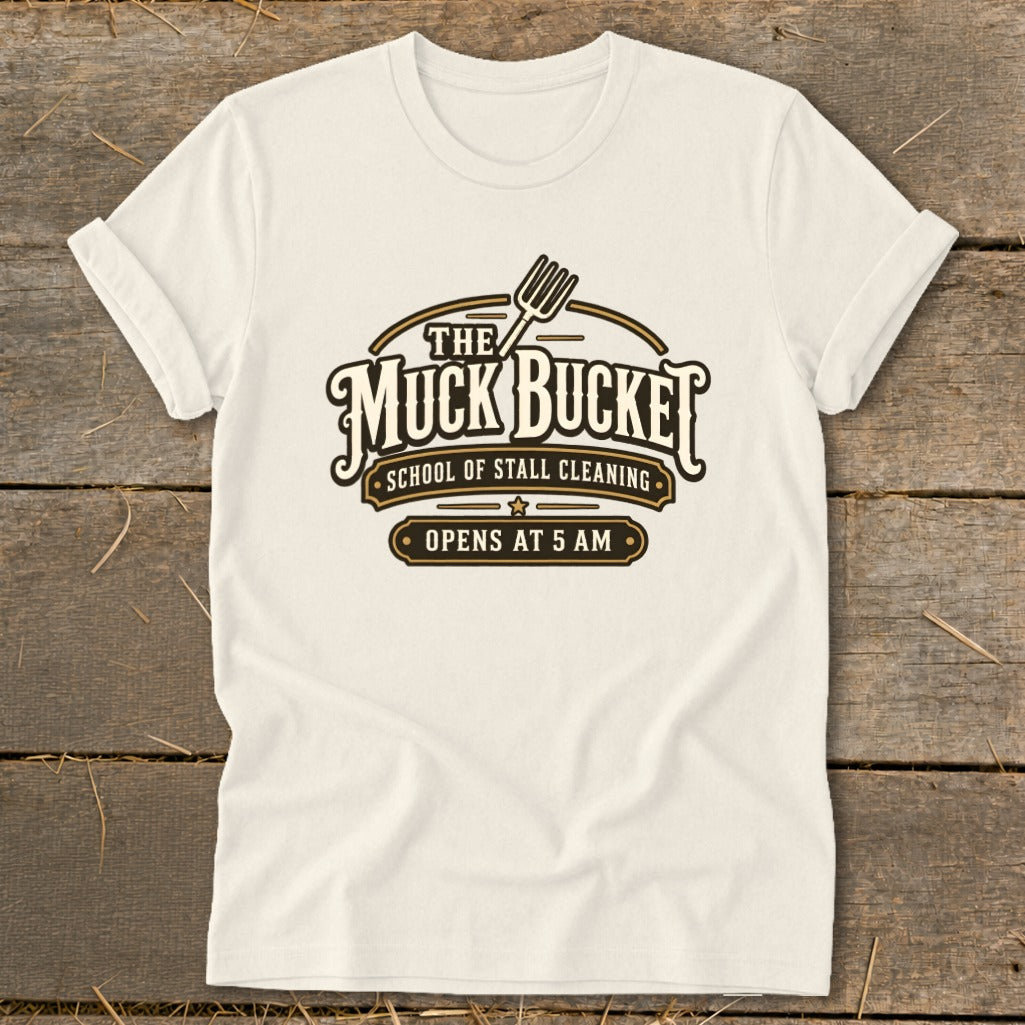Cream t-shirt with "The Muck Bucket School of Stall Cleaning Opens at 5 AM" logo.
