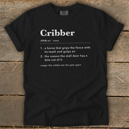 Black t-shirt featuring dictionary-style definitions for the noun cribber printed in white text on the front.