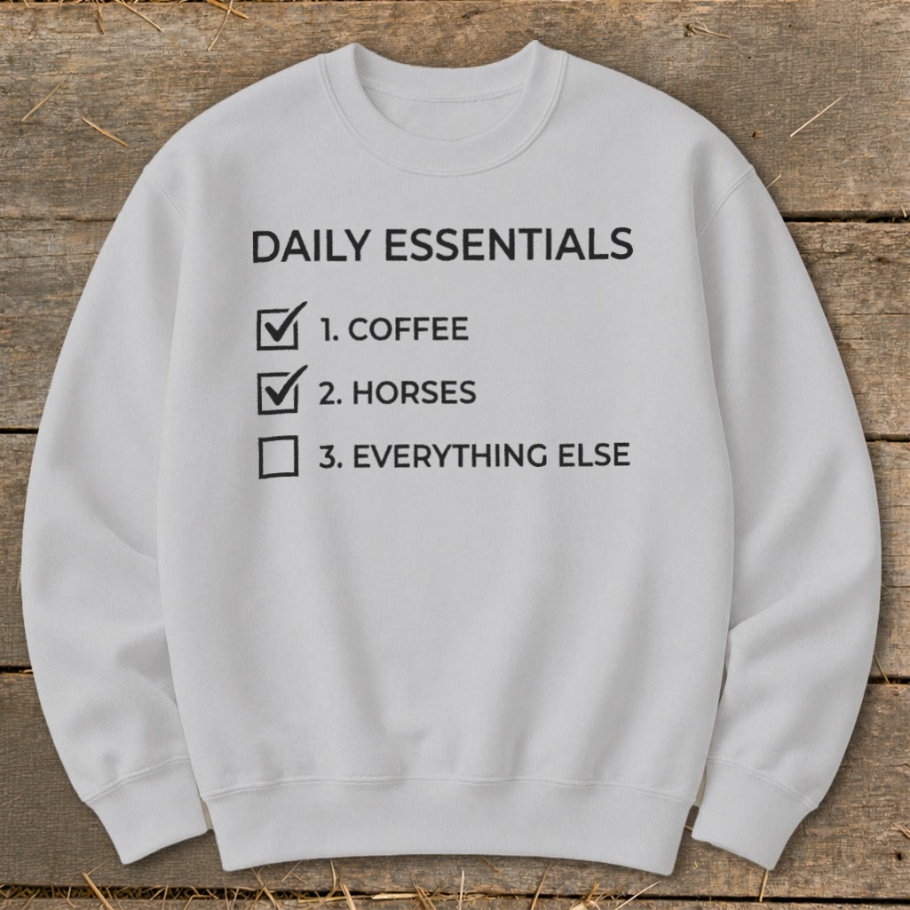 Gray sweatshirt with "Daily Essentials" checklist: coffee, horses, everything else.