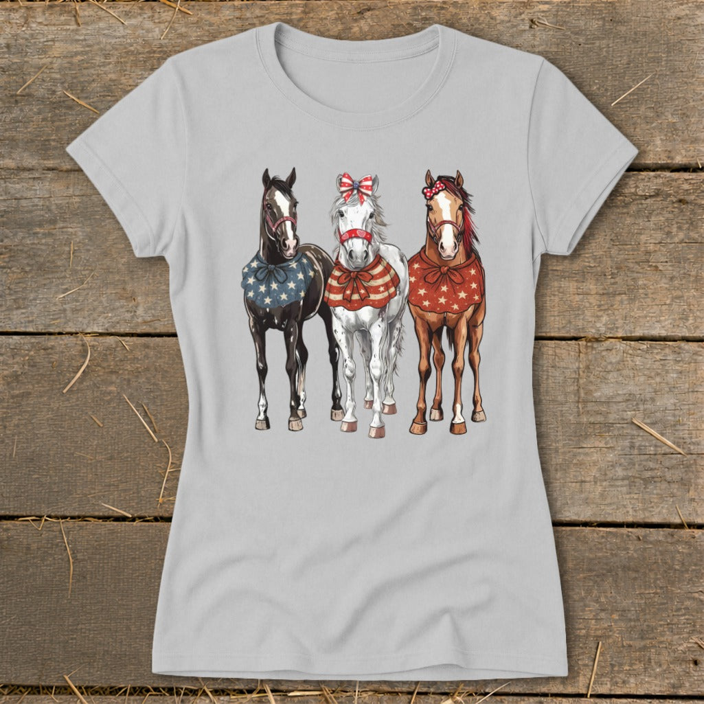Three horses in patriotic bandanas and bows are printed on a light grey t-shirt.