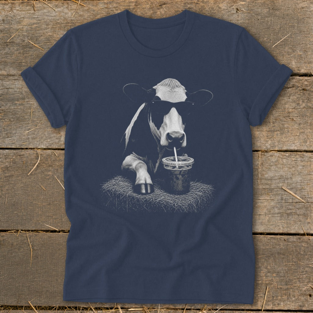 Cow wearing sunglasses drinking from a cup with a straw on a t-shirt.