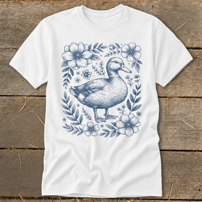 White t-shirt with a blue duck surrounded by flowers and leaves.
