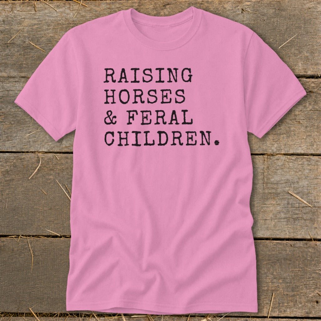 Pink t-shirt with "Raising Horses & Feral Children" printed in black text.