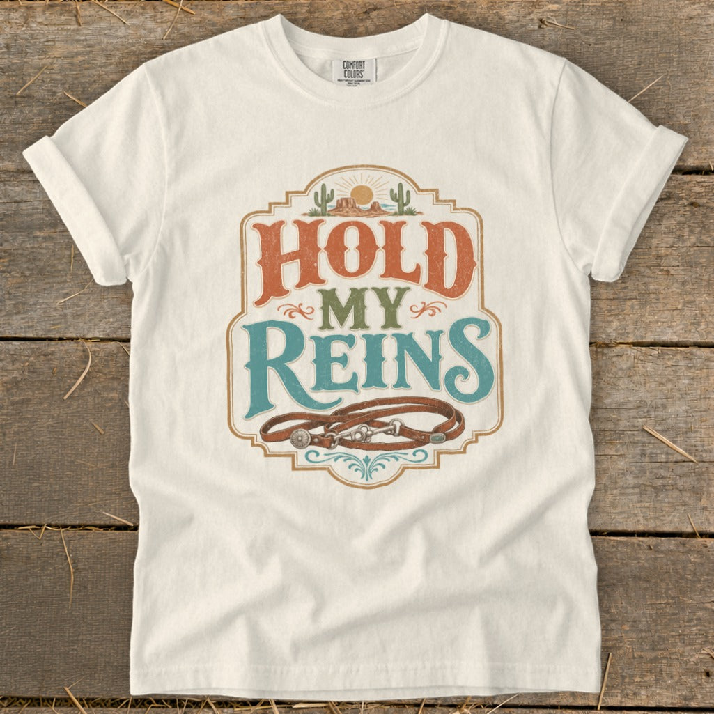 White t-shirt with "Hold My Reins" text and horse tack graphic.