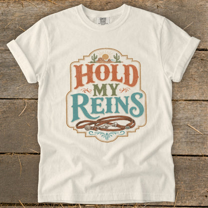 White t-shirt with "Hold My Reins" text and horse tack graphic.