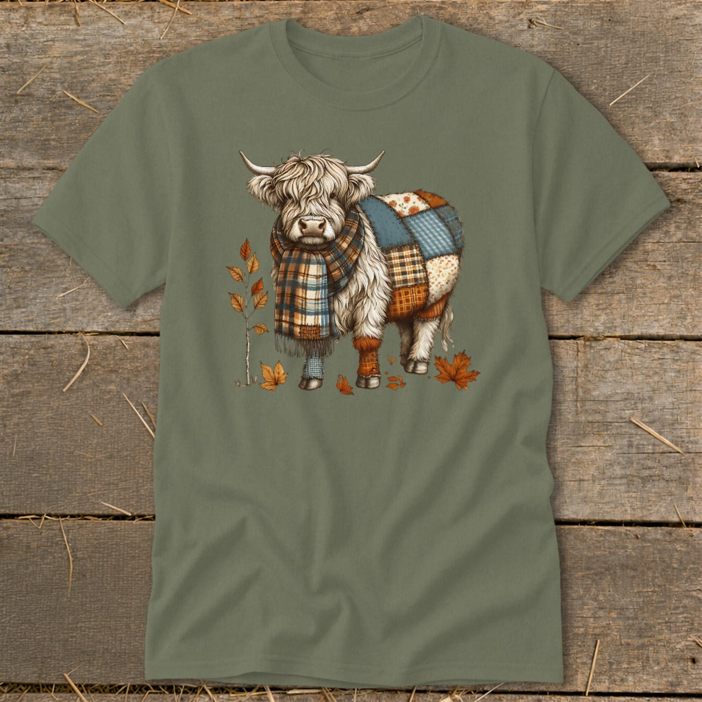 Fluffy cow wearing a patchwork blanket and plaid scarf, surrounded by autumn leaves.