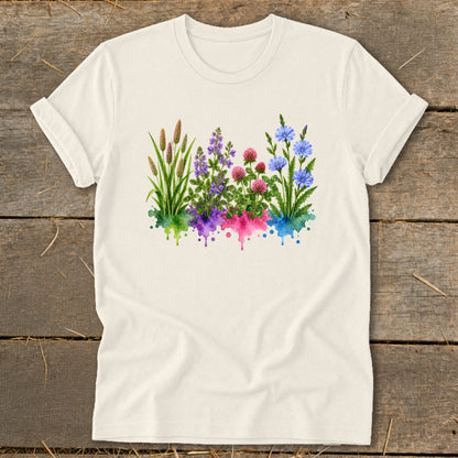 Off-white t-shirt featuring a colorful botanical watercolor print of wildflowers over green, purple, pink, and blue splatters.