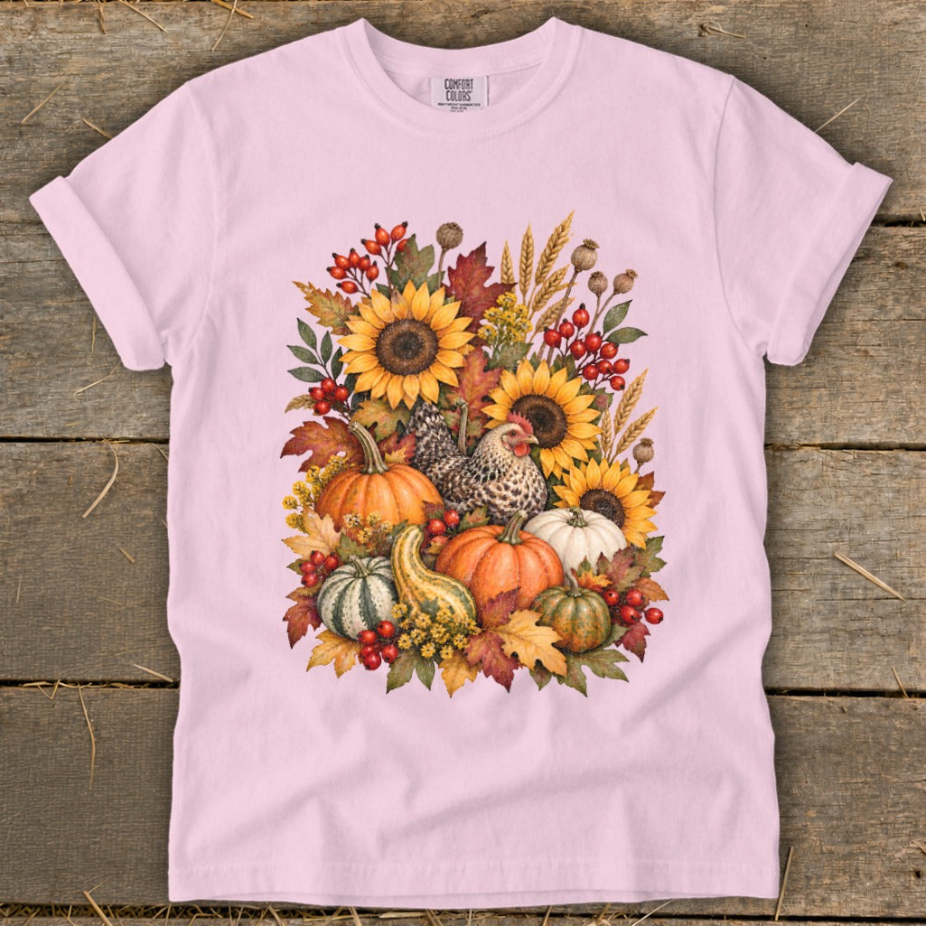 Pink t-shirt with watercolor art of sunflowers, pumpkins, a chicken, and fall foliage.