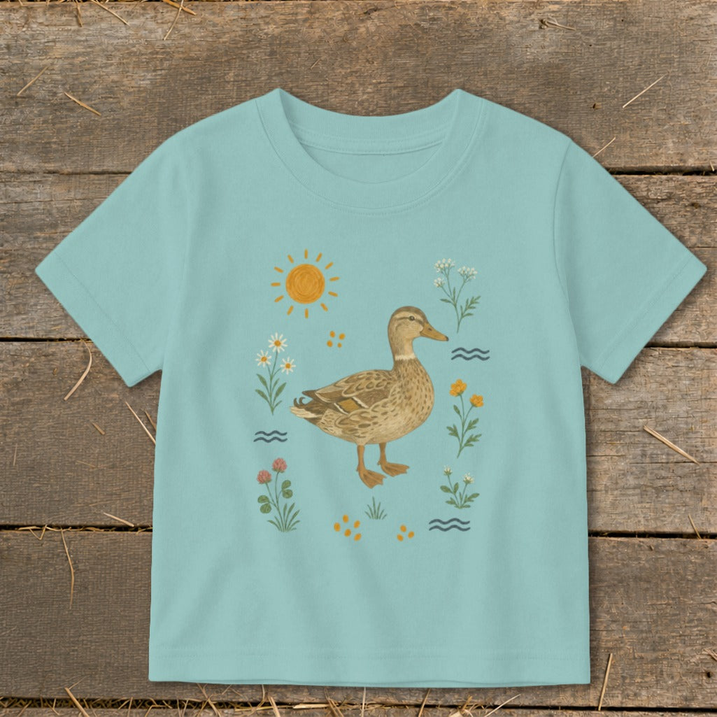 Light blue t-shirt with a duck and floral illustration under a sun.