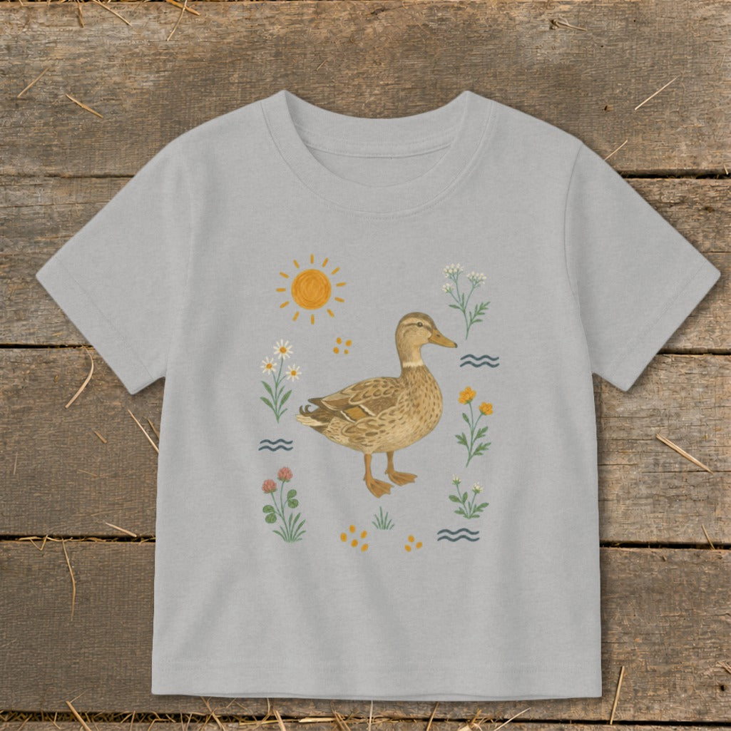 Light grey t-shirt featuring a brown duck surrounded by flowers, sun, and water.