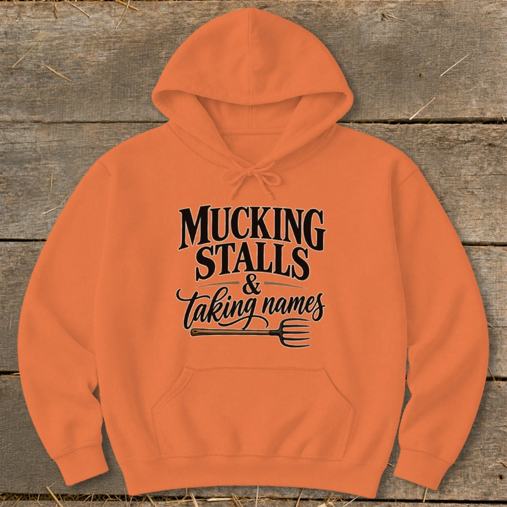 Orange hoodie with "Mucking Stalls & taking names" text and pitchfork graphic.