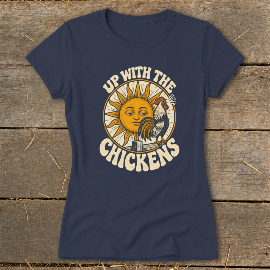 A dark blue t-shirt with a vintage graphic of a rooster crowing before a sun, featuring the text "Up With the Chickens."
