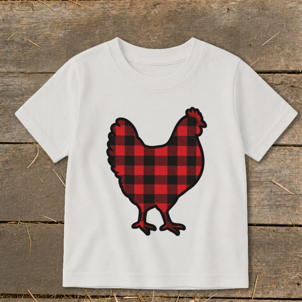 White t-shirt with a buffalo plaid chicken graphic on a wooden background.