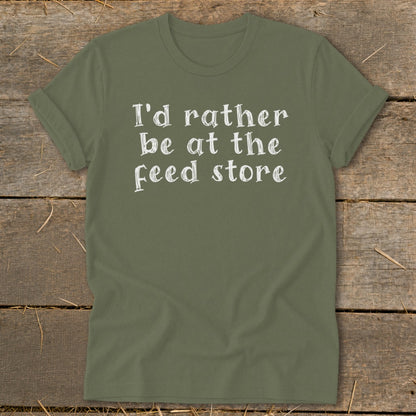 Olive green t-shirt with white text "I'd rather be at the Feed store".