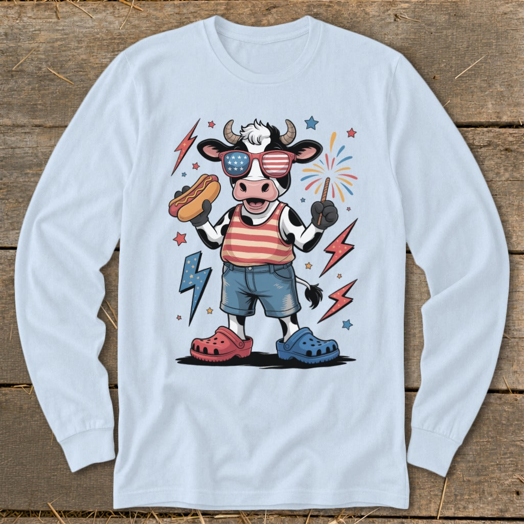 Cartoon cow in patriotic attire holding hot dog and sparkler.