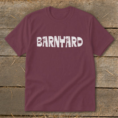 A maroon crewneck t-shirt featuring the distressed white text BARNYARD centered on the chest, laid flat on a rustic wooden background.