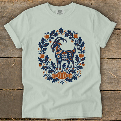Sage green t-shirt featuring a folk art graphic of a goat surrounded by autumn foliage and pumpkins.