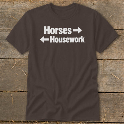 A brown crewneck t-shirt featuring white text that reads Horses with a right arrow and Housework with a left arrow.