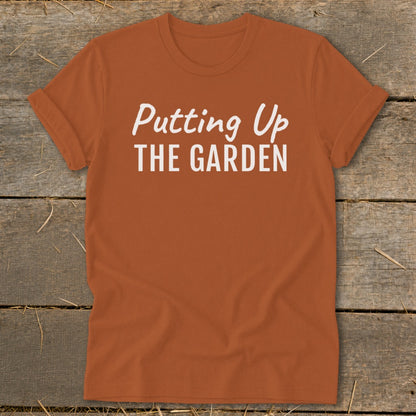 Orange t-shirt with white text reading "Putting Up THE GARDEN".