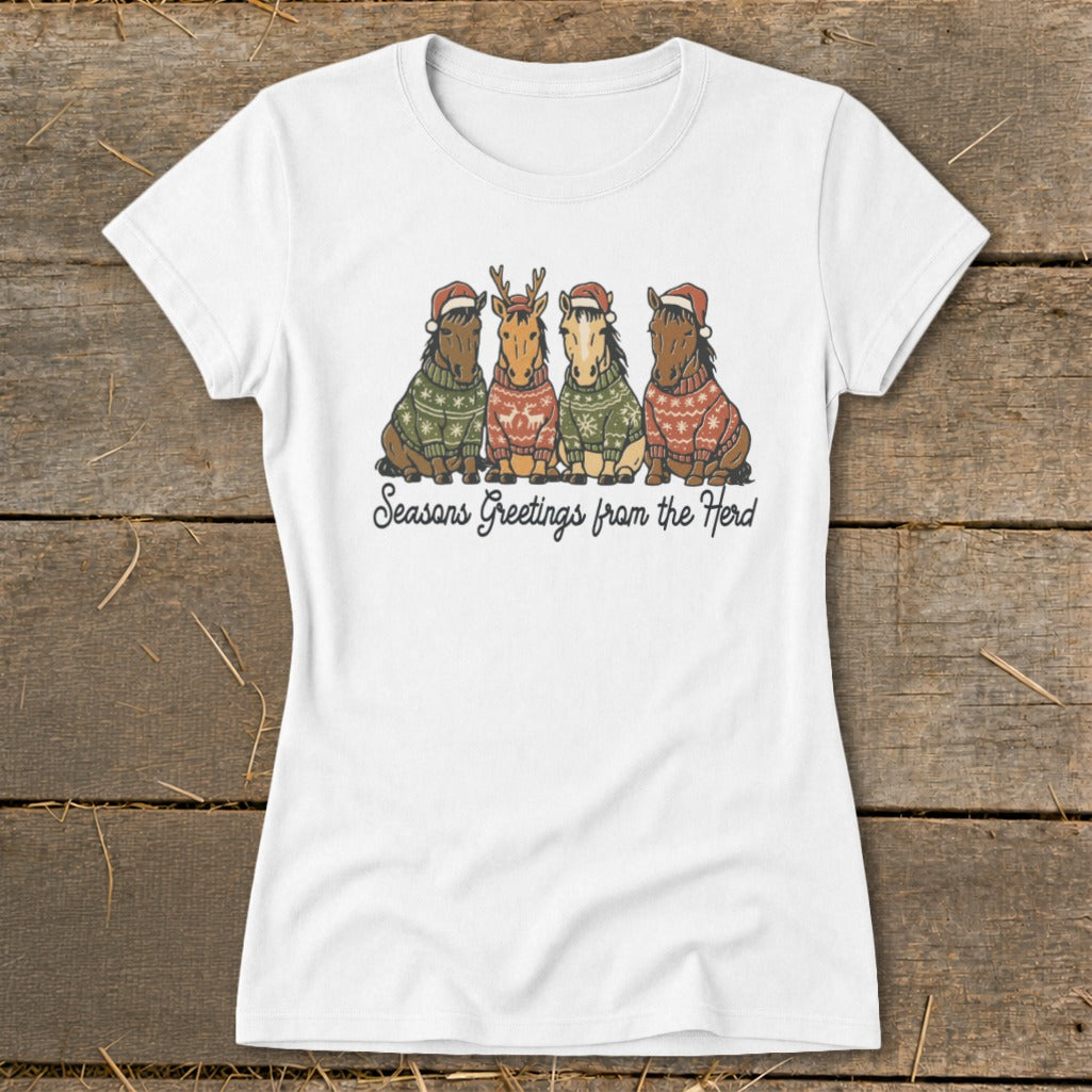 White t-shirt with four horses wearing Santa hats and sweaters, text reads "Seasons Greetings from the Herd".