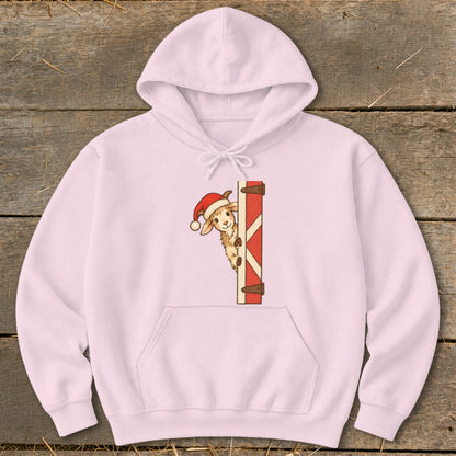 Pink hoodie with a cartoon goat wearing a Santa hat peeking from behind a red barn door.