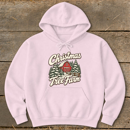 Pink hoodie with Christmas Tree Farm graphic featuring a red barn and pine trees.