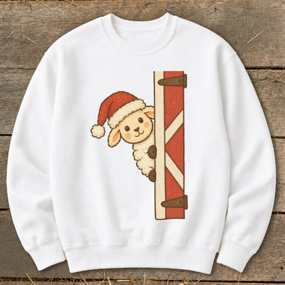 White sweatshirt with illustration of a sheep wearing Santa hat peeking from behind a barn door.