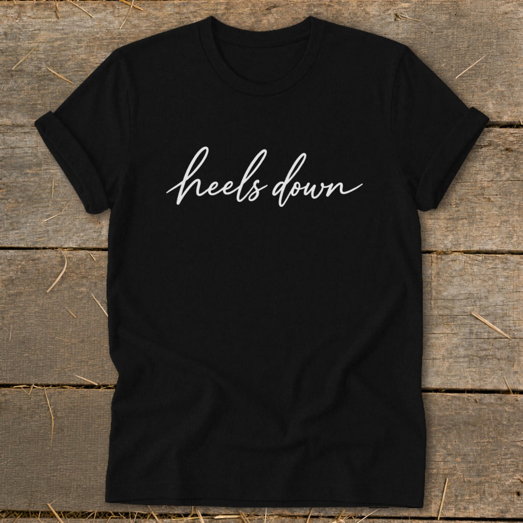 Black t-shirt with white "heels down" script text.