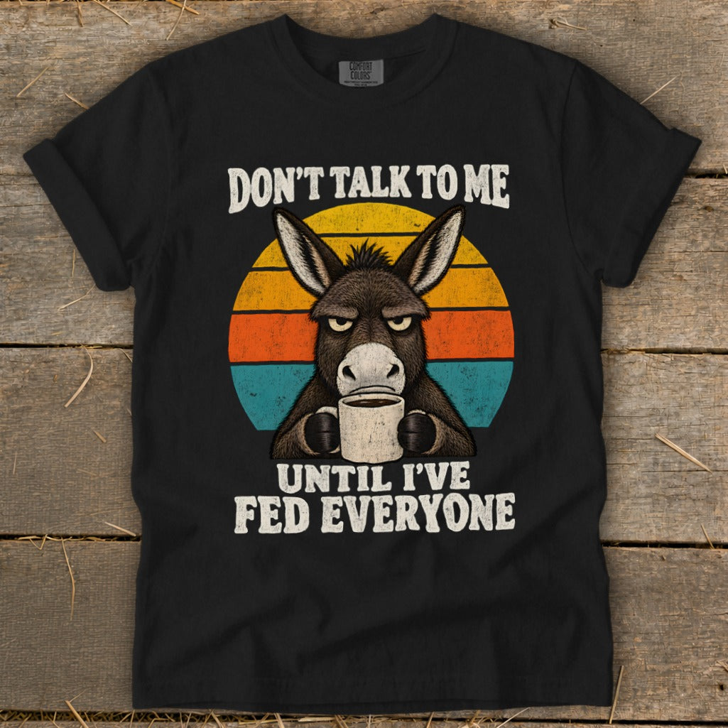 Black t-shirt featuring a graphic of an angry donkey holding a coffee mug, overlaid on a sunset graphic with the text DON'T TALK TO ME UNTIL I'VE FED EVERYONE.