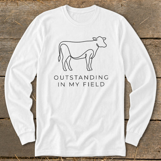 White long-sleeve shirt with a line drawing of a cow and text "Outstanding in My Field."