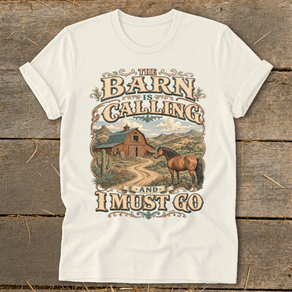 "The Barn is Calling and I Must Go" graphic on a cream t-shirt with a horse and barn scene.