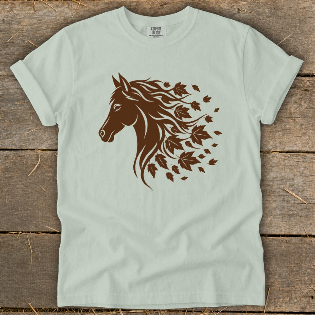 Brown horse head silhouette with flowing mane and falling leaves graphic on light green shirt.