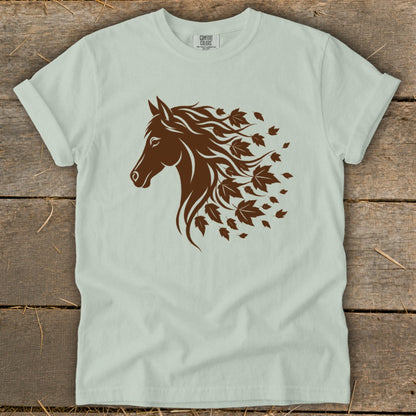 Brown horse head silhouette with flowing mane and falling leaves graphic on light green shirt.