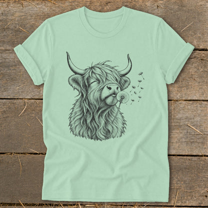 Light green t-shirt with a black sketch of a Highland cow blowing dandelion seeds.