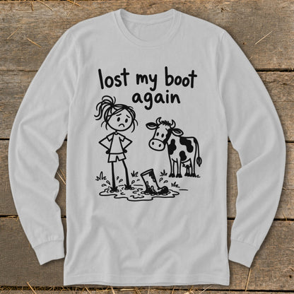 Light gray long-sleeve t-shirt with a humorous black line drawing of a girl, a cow, and a boot stuck in mud, accompanied by the text lost my boot again.