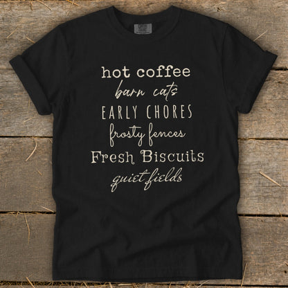 Black t-shirt with text listing "hot coffee, barn cats, early chores, frosty fences, Fresh Biscuits, quiet fields."
