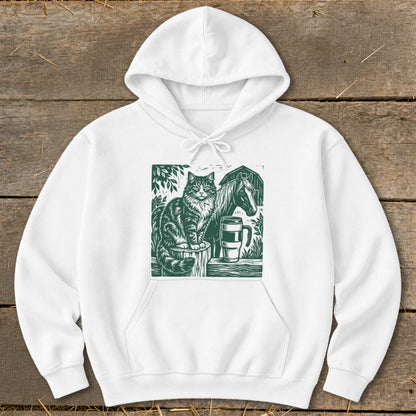 White hoodie with a green linocut print of a cat, horse, and mug.