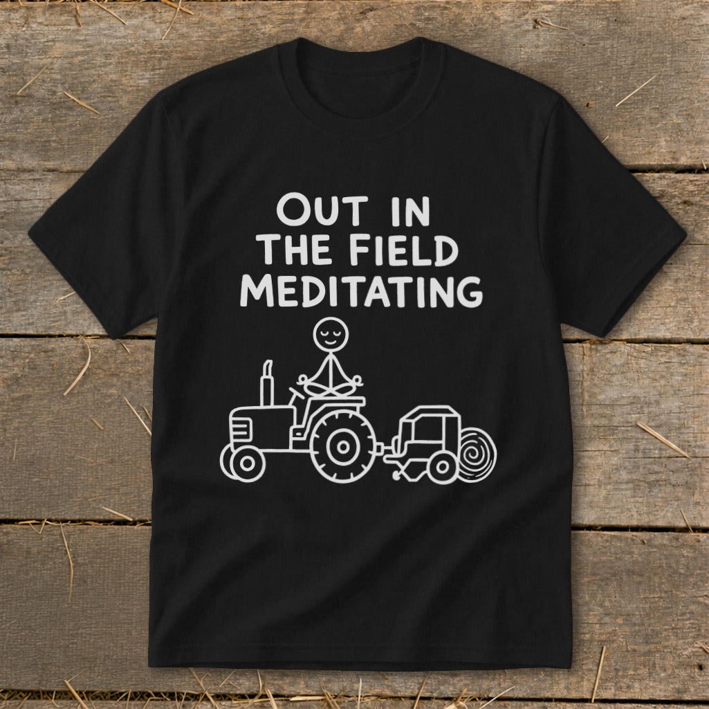 Black t-shirt with white text: "OUT IN THE FIELD MEDITATING" and a stick figure meditating on a tractor.