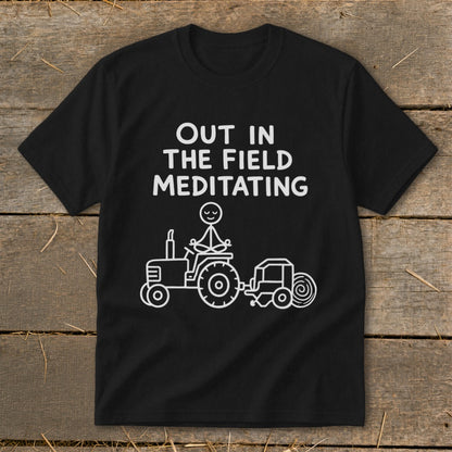 Black t-shirt with white text: "OUT IN THE FIELD MEDITATING" and a stick figure meditating on a tractor.